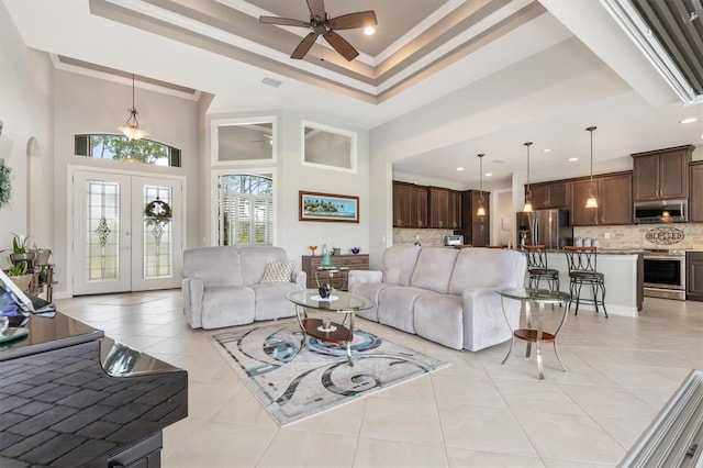 tiled living room featuring french doors, a towering ceiling, ornamental molding, and a raised ceiling