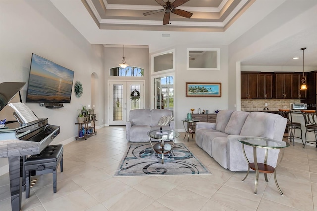 living room featuring a towering ceiling, light tile patterned floors, ceiling fan, crown molding, and french doors