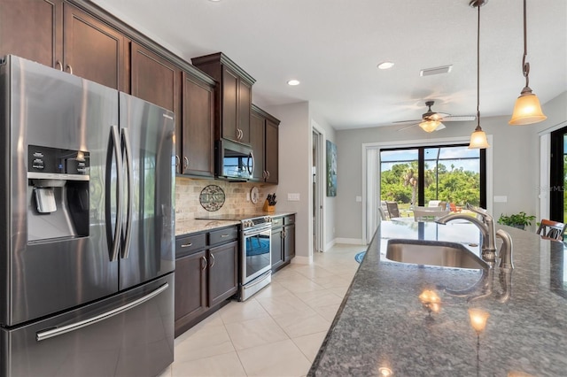 kitchen featuring sink, appliances with stainless steel finishes, dark stone countertops, hanging light fixtures, and dark brown cabinetry