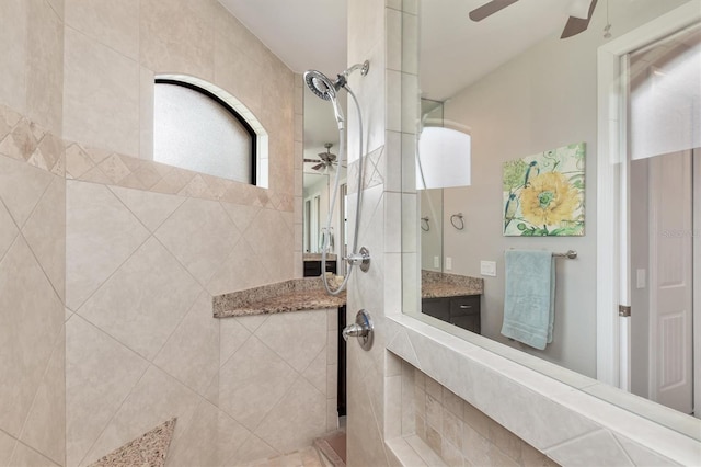 bathroom with a tile shower, vanity, and ceiling fan