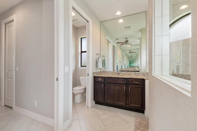 bathroom with a healthy amount of sunlight, toilet, tile patterned flooring, and vanity