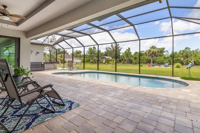 view of swimming pool with ceiling fan, a yard, glass enclosure, a patio area, and a jacuzzi