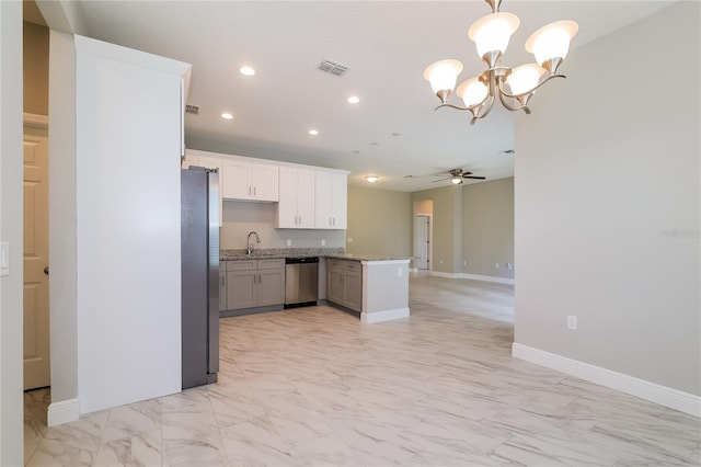 kitchen featuring ceiling fan with notable chandelier, kitchen peninsula, hanging light fixtures, appliances with stainless steel finishes, and white cabinetry