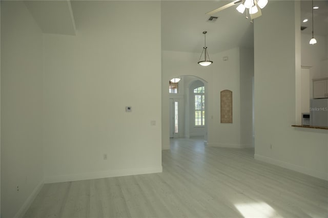 spare room featuring ceiling fan, light hardwood / wood-style floors, and a high ceiling