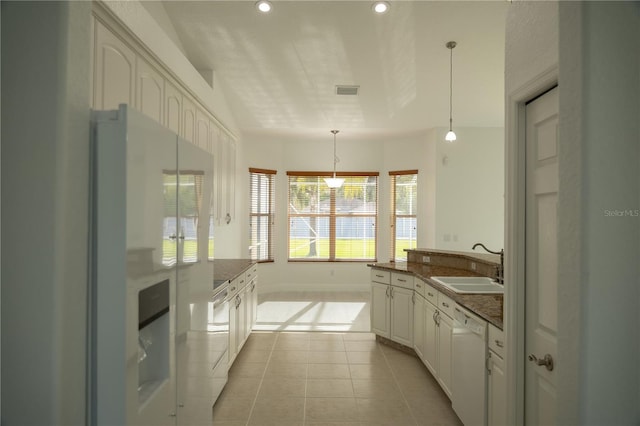 kitchen featuring white dishwasher, sink, pendant lighting, light tile patterned floors, and white cabinets