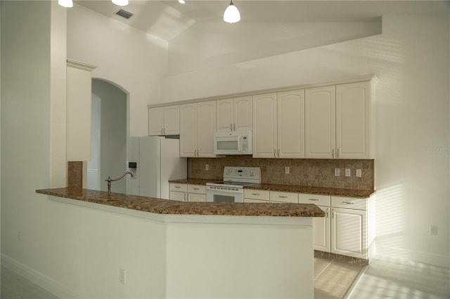 kitchen with tasteful backsplash, high vaulted ceiling, kitchen peninsula, white appliances, and white cabinets