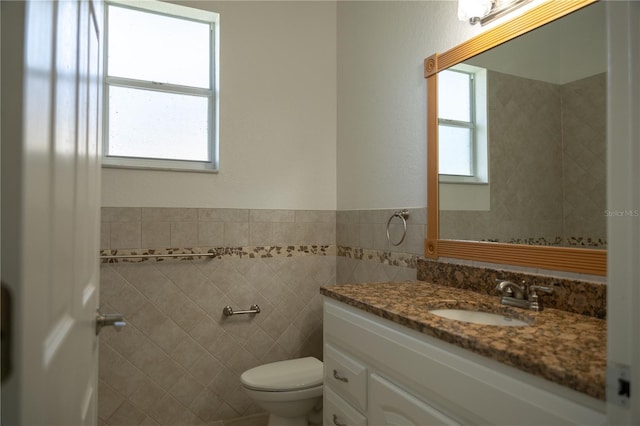 bathroom featuring vanity, toilet, and tile walls