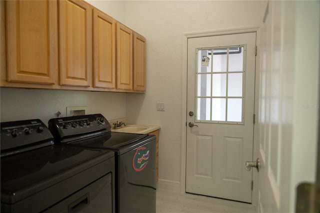 clothes washing area with cabinets, independent washer and dryer, sink, and light wood-type flooring