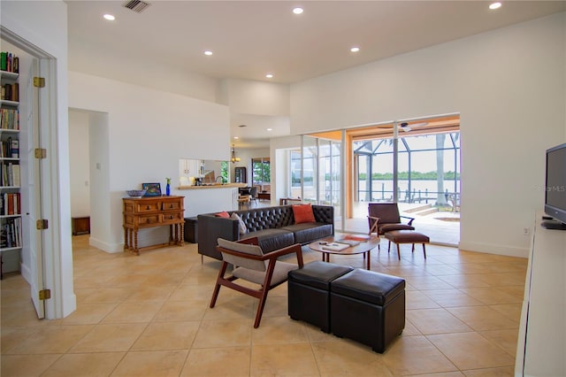 living room featuring a towering ceiling, a healthy amount of sunlight, and light tile patterned floors