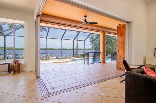 entryway featuring light tile patterned flooring, a water view, a healthy amount of sunlight, and ceiling fan