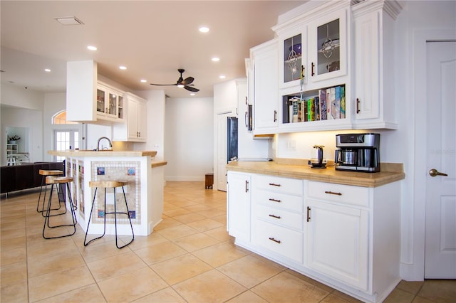 kitchen with white cabinetry, ceiling fan, a breakfast bar, and light tile patterned floors