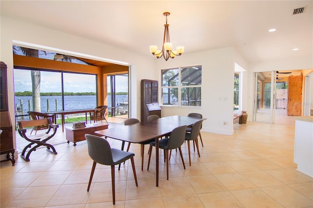 dining area featuring light tile patterned flooring, a water view, and an inviting chandelier