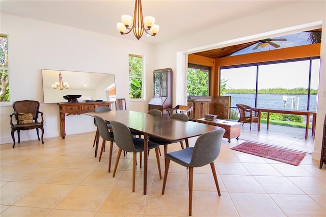 tiled dining area with vaulted ceiling, ceiling fan with notable chandelier, a water view, and a wealth of natural light