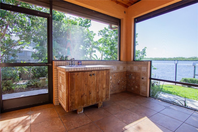 unfurnished sunroom featuring sink and a water view