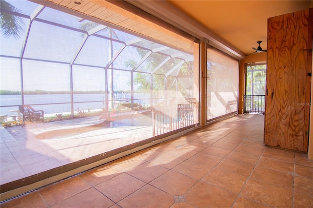 unfurnished sunroom with ceiling fan and a water view