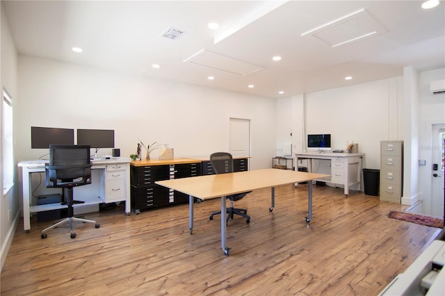 office space featuring a wall mounted AC and light hardwood / wood-style flooring