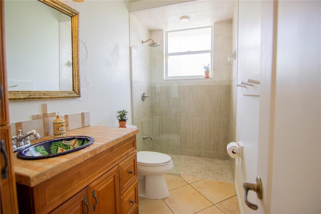 bathroom featuring tiled shower, vanity, toilet, and tile patterned flooring