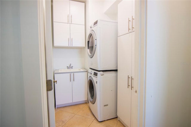 clothes washing area with cabinets, stacked washer and clothes dryer, sink, and light tile patterned floors