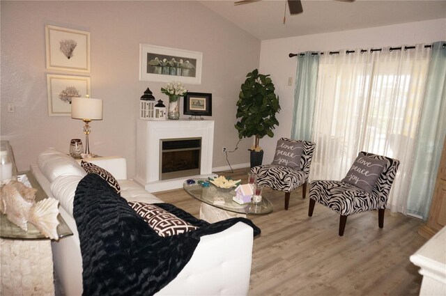 living room with ceiling fan, wood-type flooring, and lofted ceiling