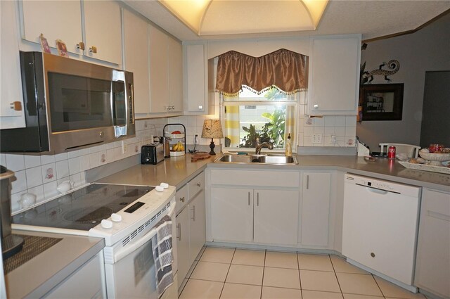 kitchen featuring light tile patterned floors, white appliances, white cabinetry, and sink