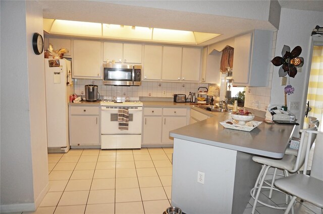 kitchen featuring white appliances, white cabinets, sink, light tile patterned floors, and tasteful backsplash