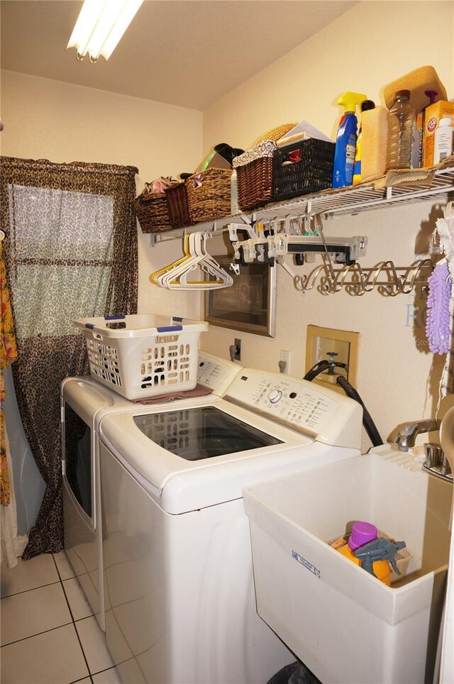 clothes washing area featuring tile patterned floors, separate washer and dryer, and sink