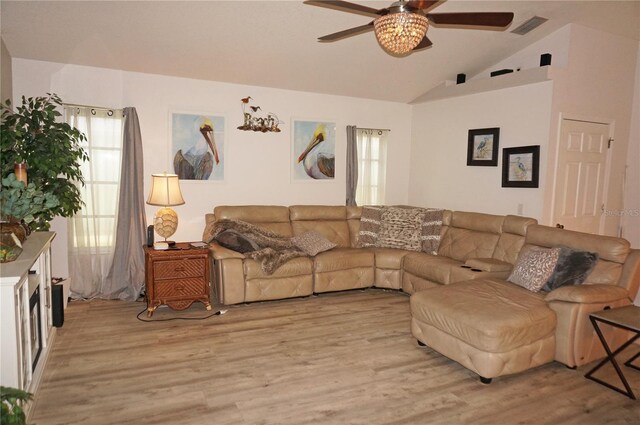 living room with ceiling fan, light hardwood / wood-style floors, and vaulted ceiling