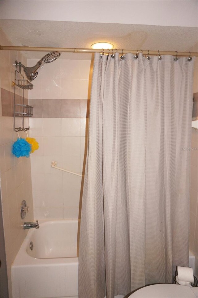 bathroom featuring shower / bath combination with curtain and toilet