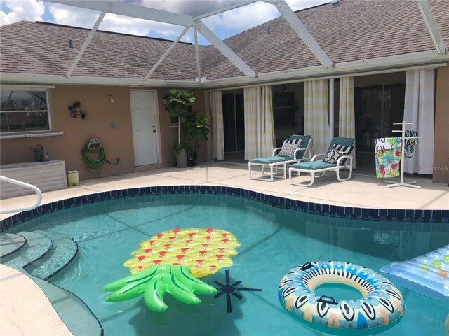 view of swimming pool featuring glass enclosure and a patio area