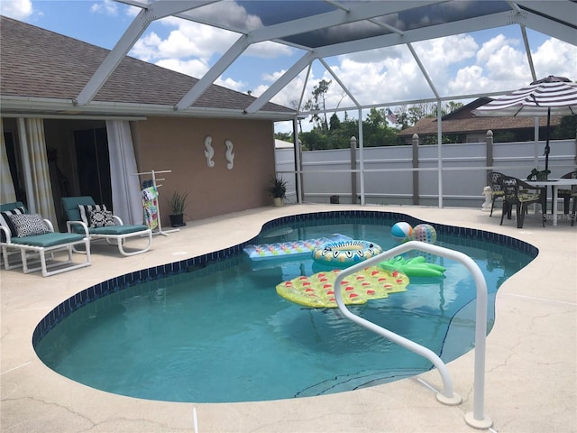 view of pool with glass enclosure and a patio