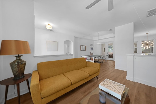 living room featuring wood-type flooring and ceiling fan with notable chandelier