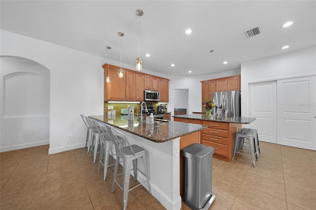 kitchen featuring decorative backsplash, decorative light fixtures, a kitchen bar, kitchen peninsula, and stainless steel appliances