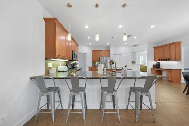 kitchen with pendant lighting, a breakfast bar, dark stone countertops, and stainless steel appliances