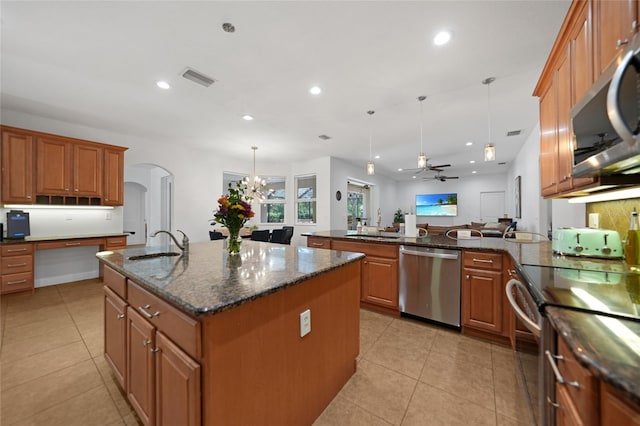 kitchen with pendant lighting, a center island with sink, ceiling fan with notable chandelier, sink, and stainless steel appliances