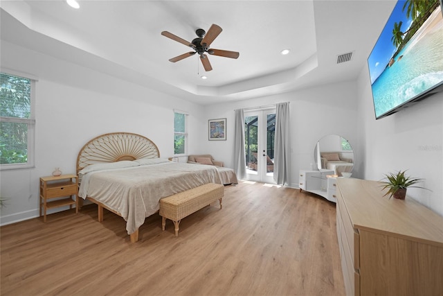 bedroom featuring access to exterior, ceiling fan, french doors, light hardwood / wood-style floors, and a tray ceiling