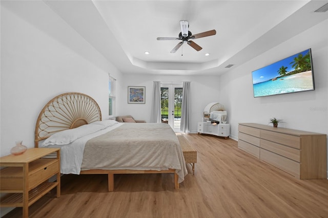 bedroom with ceiling fan, a raised ceiling, access to outside, and light hardwood / wood-style flooring