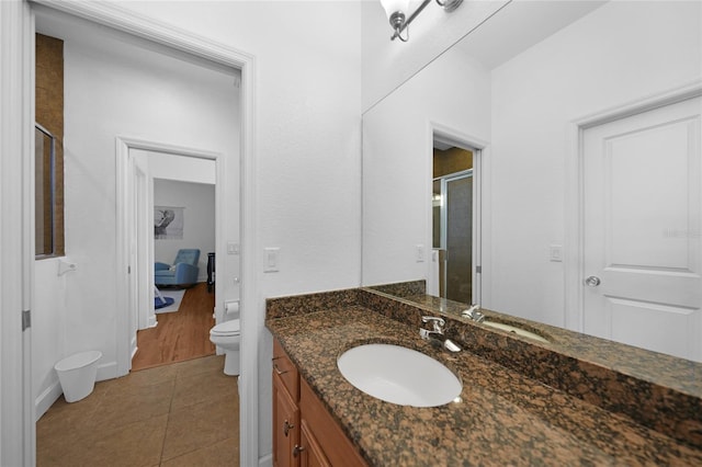 bathroom with walk in shower, tile patterned flooring, vanity, and toilet