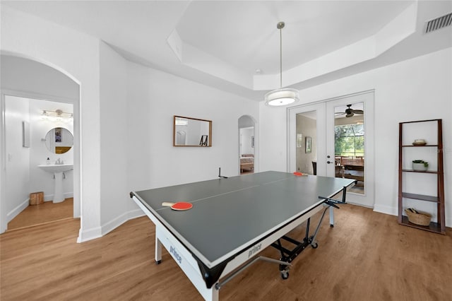 recreation room with ceiling fan, sink, french doors, a raised ceiling, and light hardwood / wood-style floors