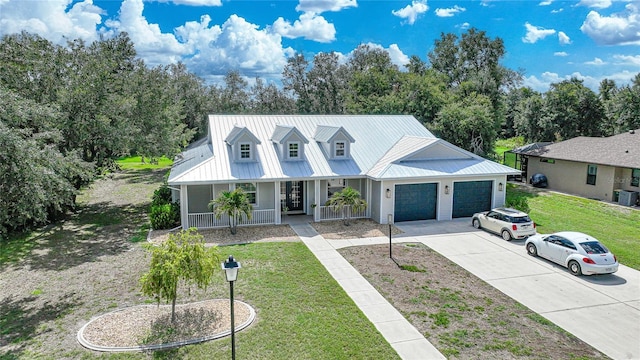 view of front of house with central AC unit, a garage, covered porch, and a front lawn