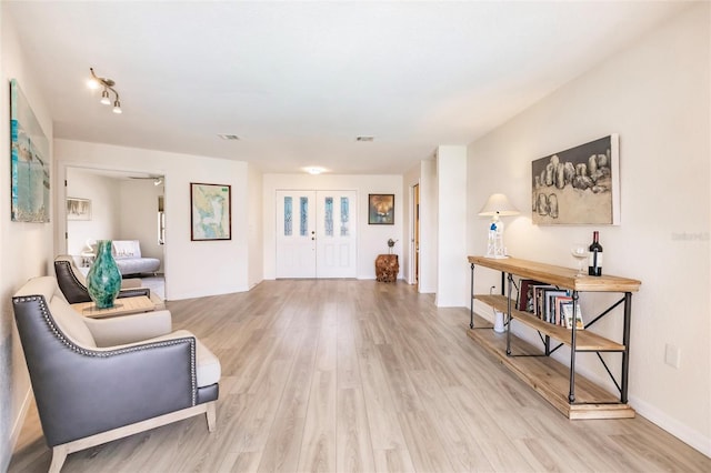 living area with french doors and light hardwood / wood-style flooring