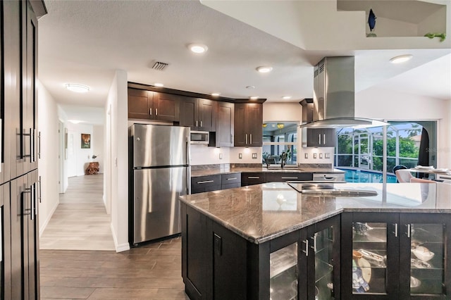 kitchen with hardwood / wood-style floors, range hood, stone countertops, dark brown cabinetry, and stainless steel appliances