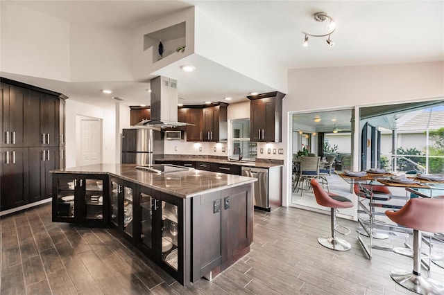 kitchen with vaulted ceiling, a kitchen island, dark brown cabinetry, island exhaust hood, and stainless steel appliances