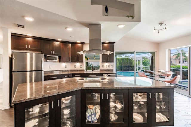 kitchen featuring island exhaust hood, dark brown cabinetry, stainless steel appliances, stone counters, and lofted ceiling