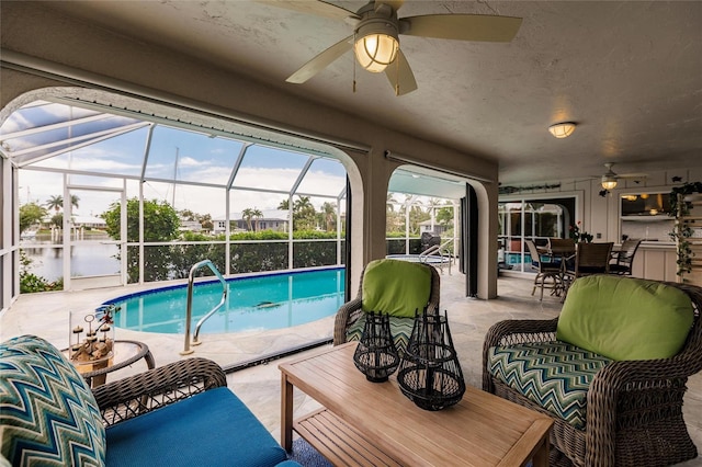 view of swimming pool with ceiling fan, a patio area, a water view, and an outdoor hangout area