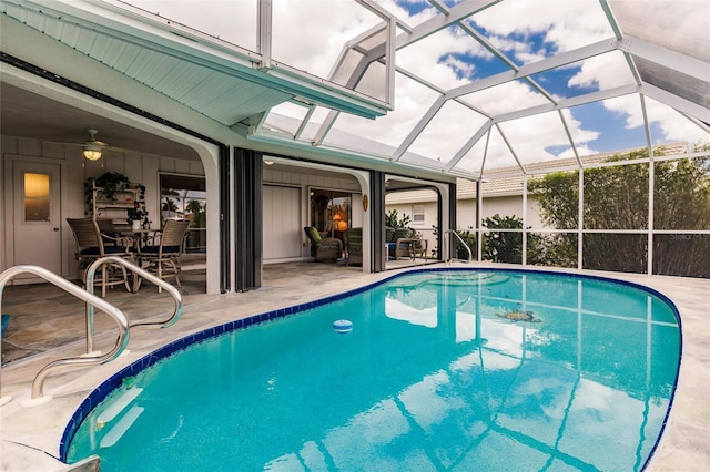 view of swimming pool featuring glass enclosure, ceiling fan, and a patio