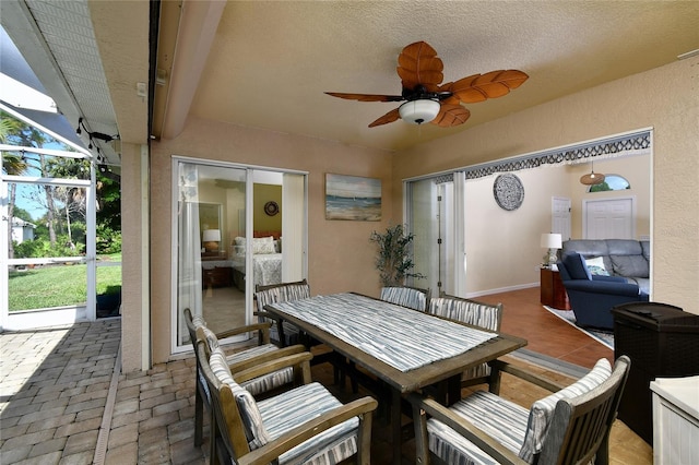 view of patio featuring ceiling fan and glass enclosure