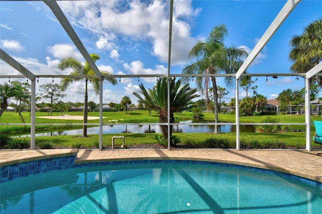 view of pool with a yard, glass enclosure, and a water view