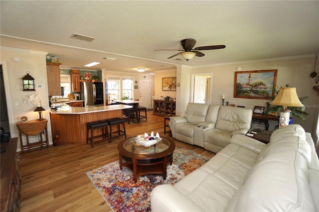 living room featuring light hardwood / wood-style flooring, ceiling fan, and ornamental molding