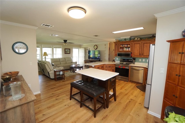 kitchen featuring kitchen peninsula, light wood-type flooring, ornamental molding, stainless steel appliances, and ceiling fan