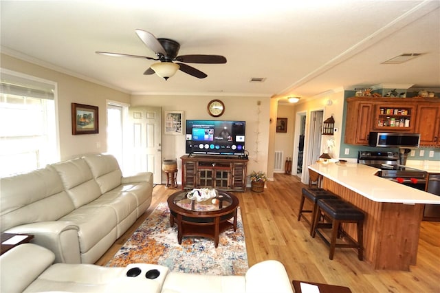 living room with light hardwood / wood-style floors, ceiling fan, and crown molding